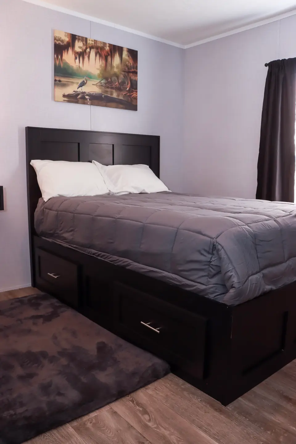 Bedroom with a dark wood storage bed, gray comforter and white pillows